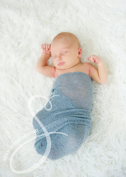 Newborn Boy wrapped in blue on white fur