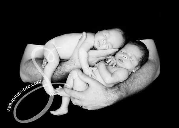 Twin newborn boys in dad's arms black and white
